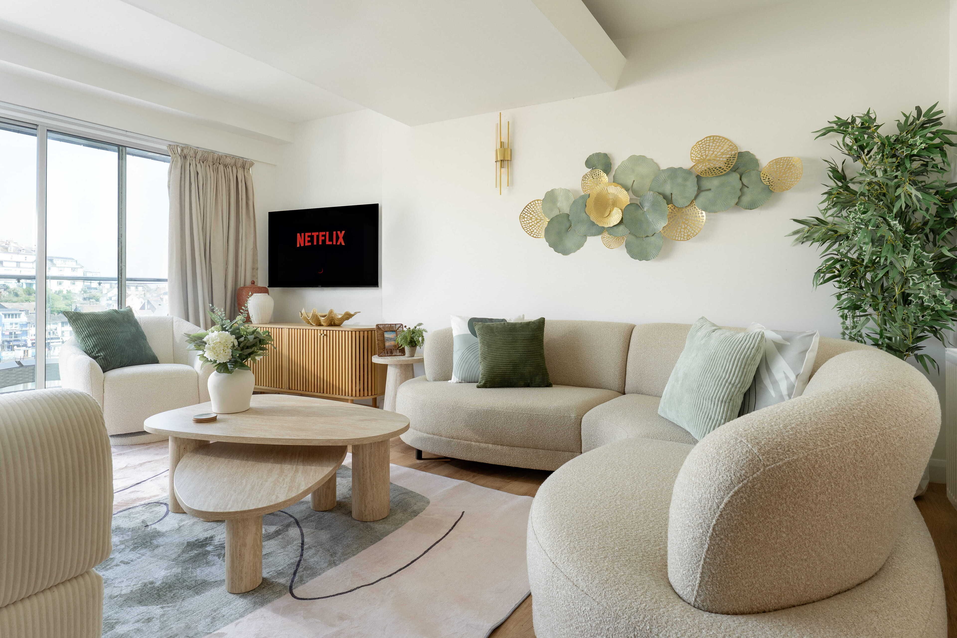 A modern living room with a sofa, coffee table, and a flat-screen TV displaying Netflix.