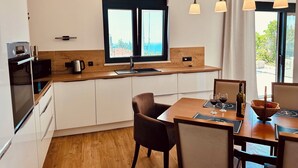 A modern kitchen with a wooden countertop, a built-in oven, and a window with a view. - Serenity House—Private Infinity Pool, Panoramic Sea Views, and Near Budva (Krimovica)