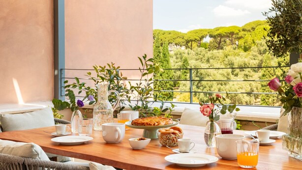 Zona pranzo con tavolo apparecchiato per due, con vista su un paesaggio verdeggiante.