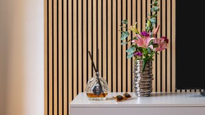 A modern interior with a wooden slat wall, a white console table, and a vase with flowers. - Comfort & Luxury at the Colosseum - Entire Apartment (Rome)