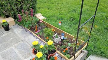 Um jardim com canteiros elevados, plantas em vasos e enfeites de jardim.