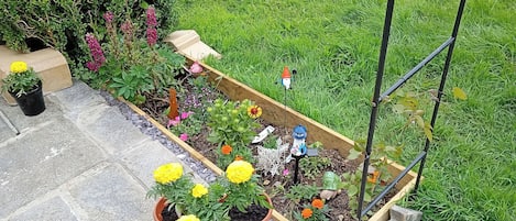A garden with raised beds, potted plants, and garden decorations.