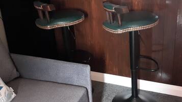Dos taburetes de bar con asientos acolchados y base redonda, ubicados frente a una pared de madera.