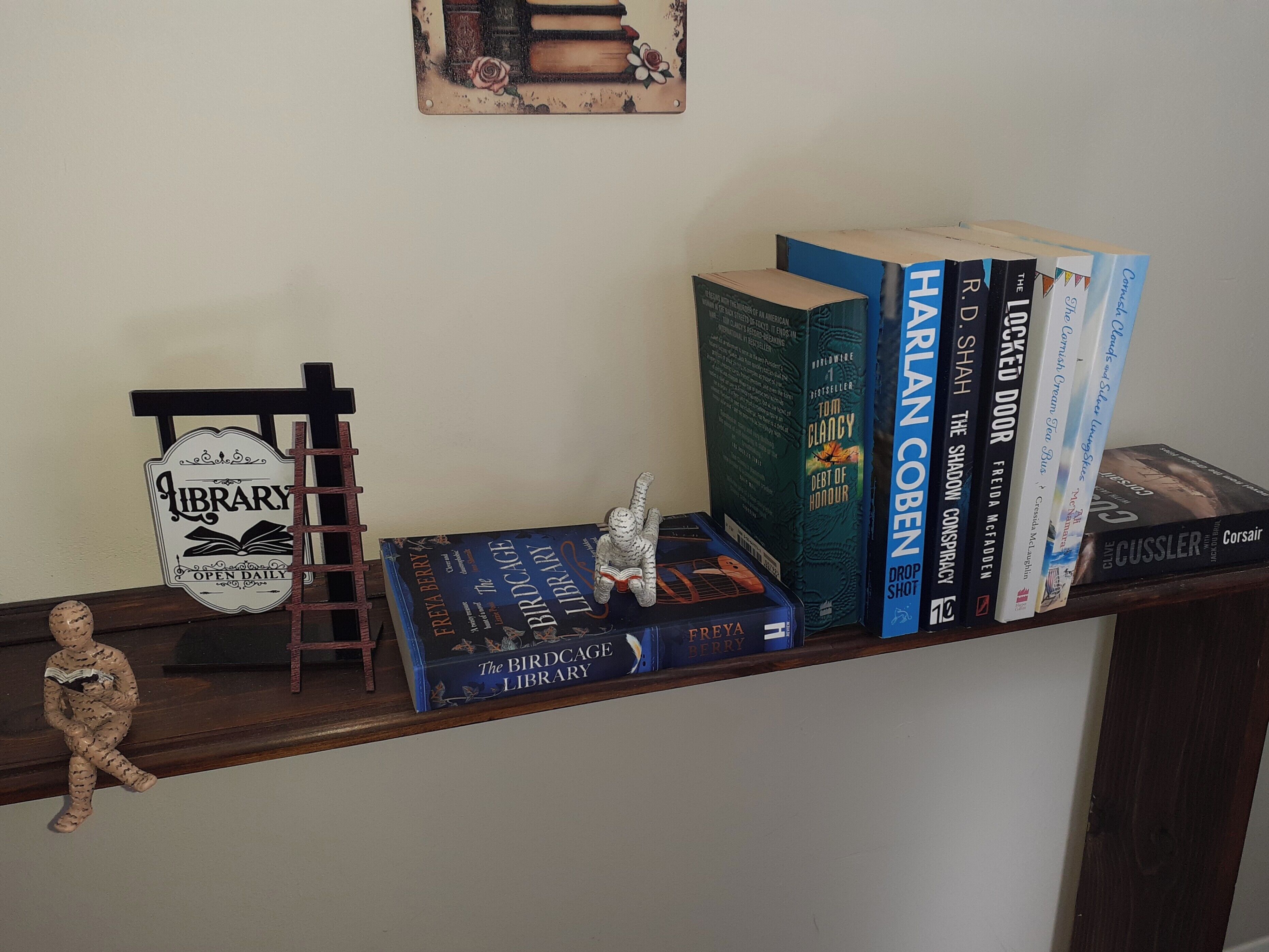 Una estantería con libros y una pequeña figurita.