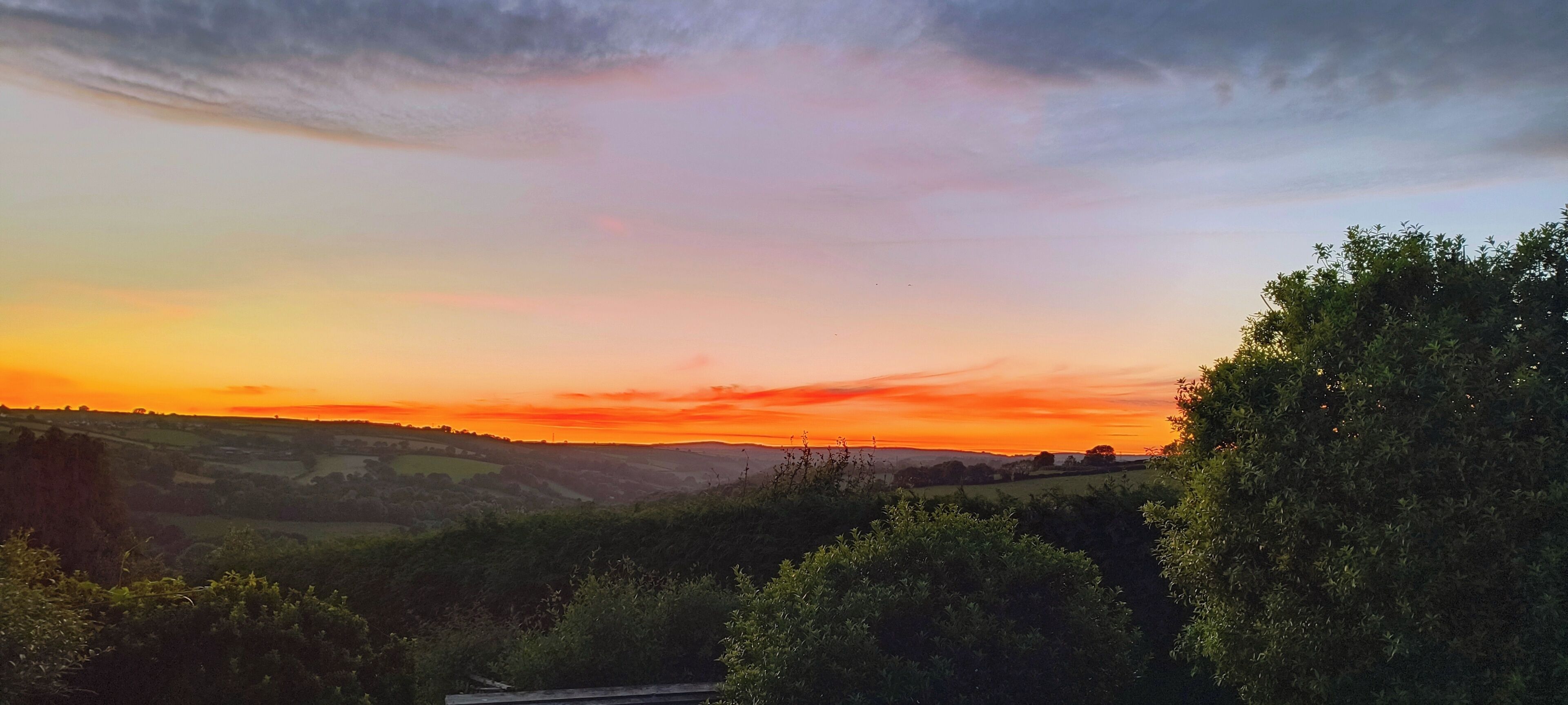 Un paisaje con colinas ondulantes y un cielo al atardecer.