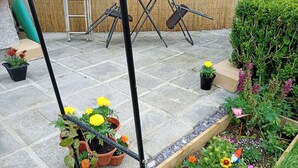 Un jardí amb plantes en testos, un gnom de jardí i una caixa de plantació de fusta.