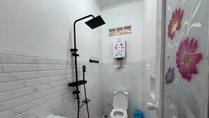 A bathroom with a shower, toilet, sink, and a glass door with floral decals.