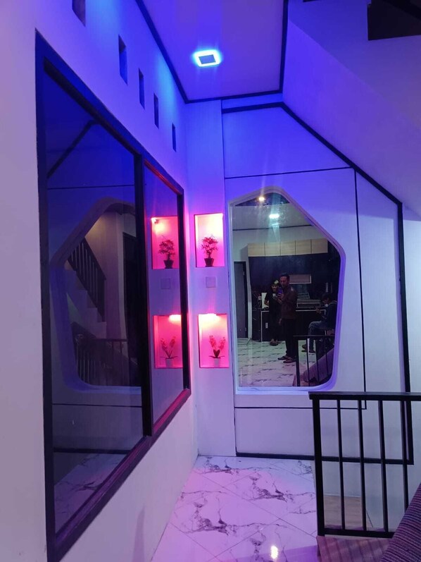 Un intérieur moderne avec un escalier, des murs en verre et des plantes en pot éclairées.