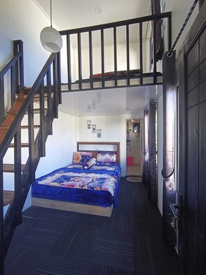 A bedroom with a bed, a staircase, and a door.