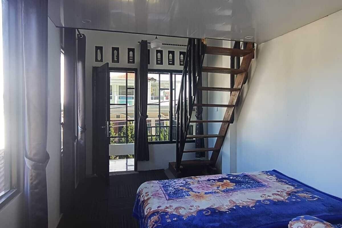 Ein Zimmer mit Bett, Fenster, Tür und einer Treppe.