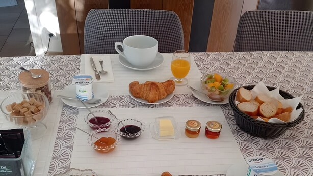 A breakfast table with croissants, fruit, juice, and condiments.