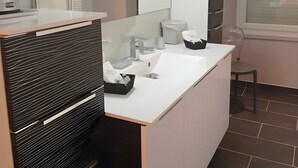A modern bathroom with a white vanity, a large mirror, and a window.