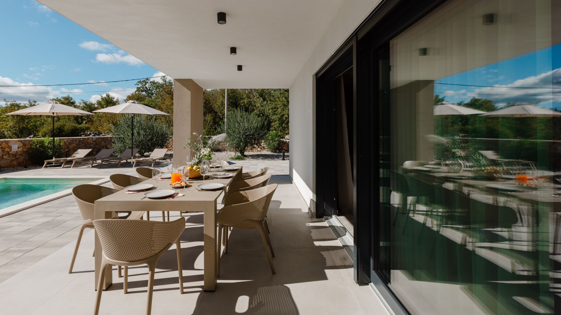 An outdoor dining area with a pool, lounge chairs, and umbrellas.