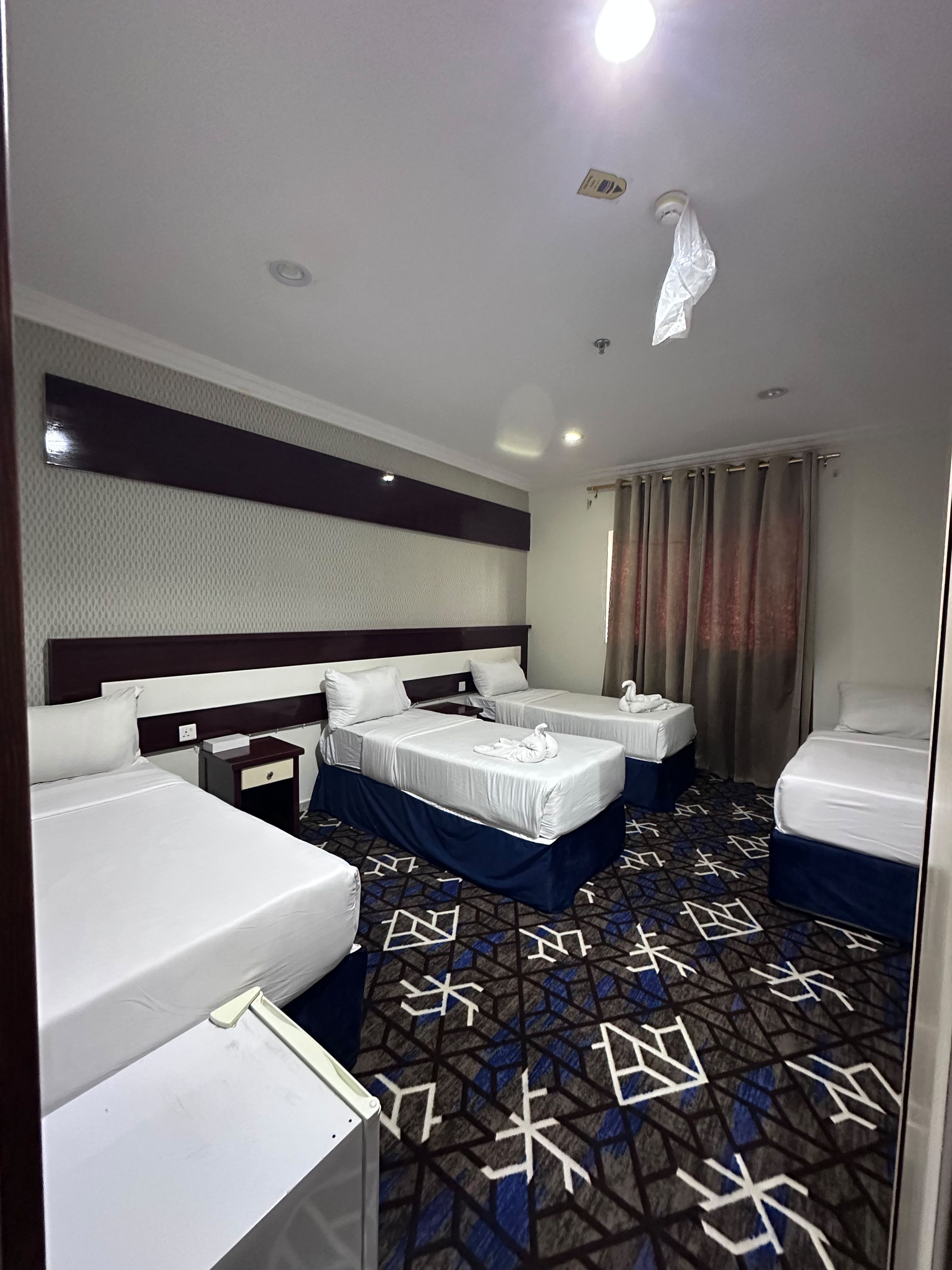 Una habitación de hotel con dos camas, una mesita pequeña y una alfombra estampada.