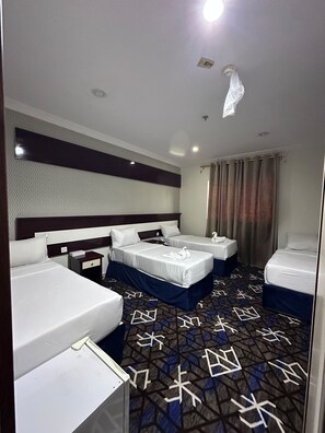A hotel room with two beds, a small table, and a patterned carpet. - Durrat Al-Ijaba Hotel (Makkah)