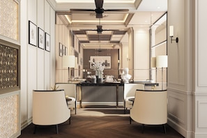 A hotel lobby with a central reception desk, two seating areas with chairs, a ceiling fan, and framed pictures on the walls. - RatiLanna Nimman (Chiang Mai)