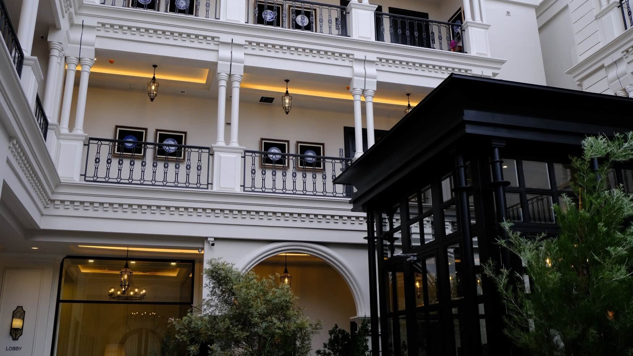 A multi-story building with a grand entrance, balconies with railings, and a lobby area.