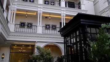 A multi-story building with a grand entrance, balconies with railings, and a lobby area.