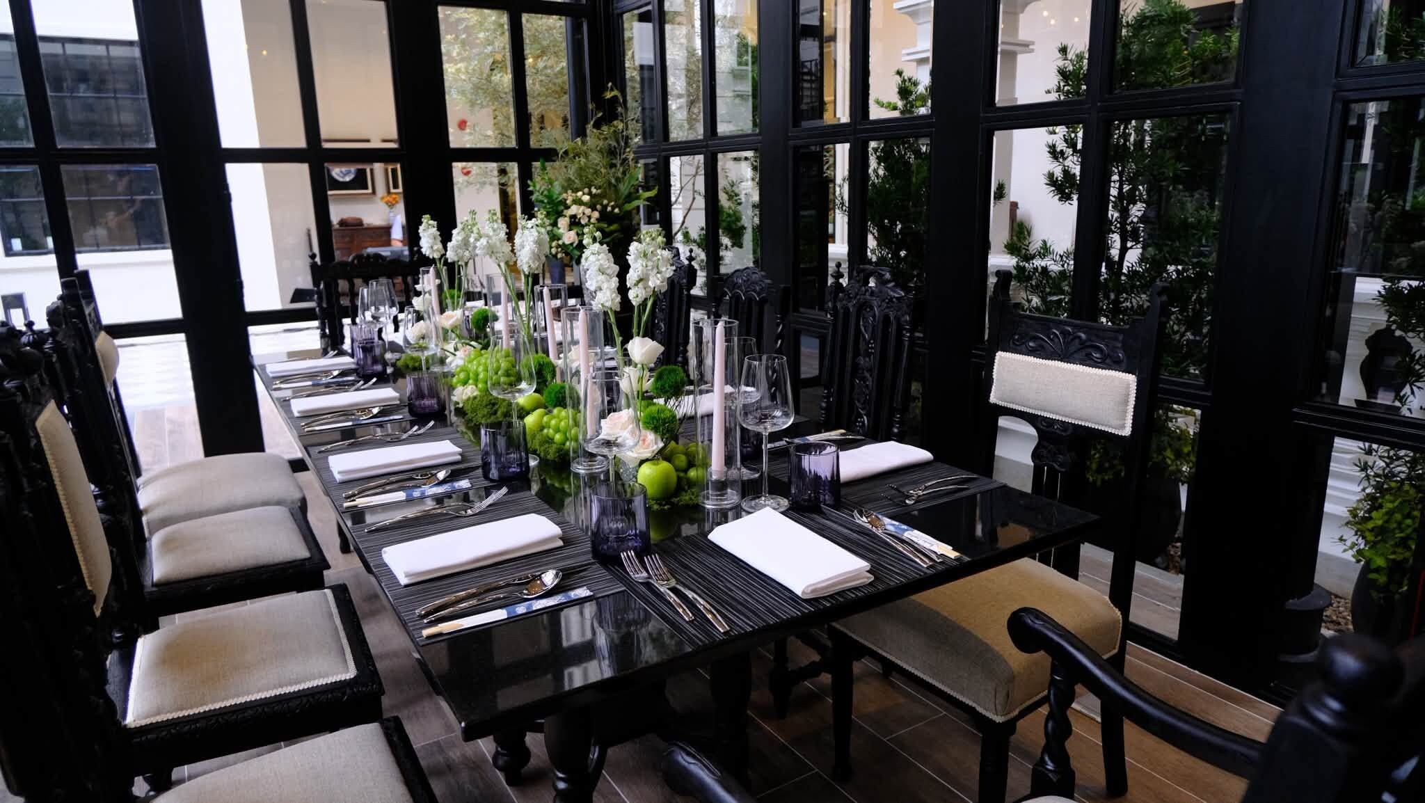 Un comedor con una larga mesa dispuesta para una comida, rodeada de sillas.