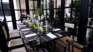 A dining area with a long table set for a meal, surrounded by chairs.