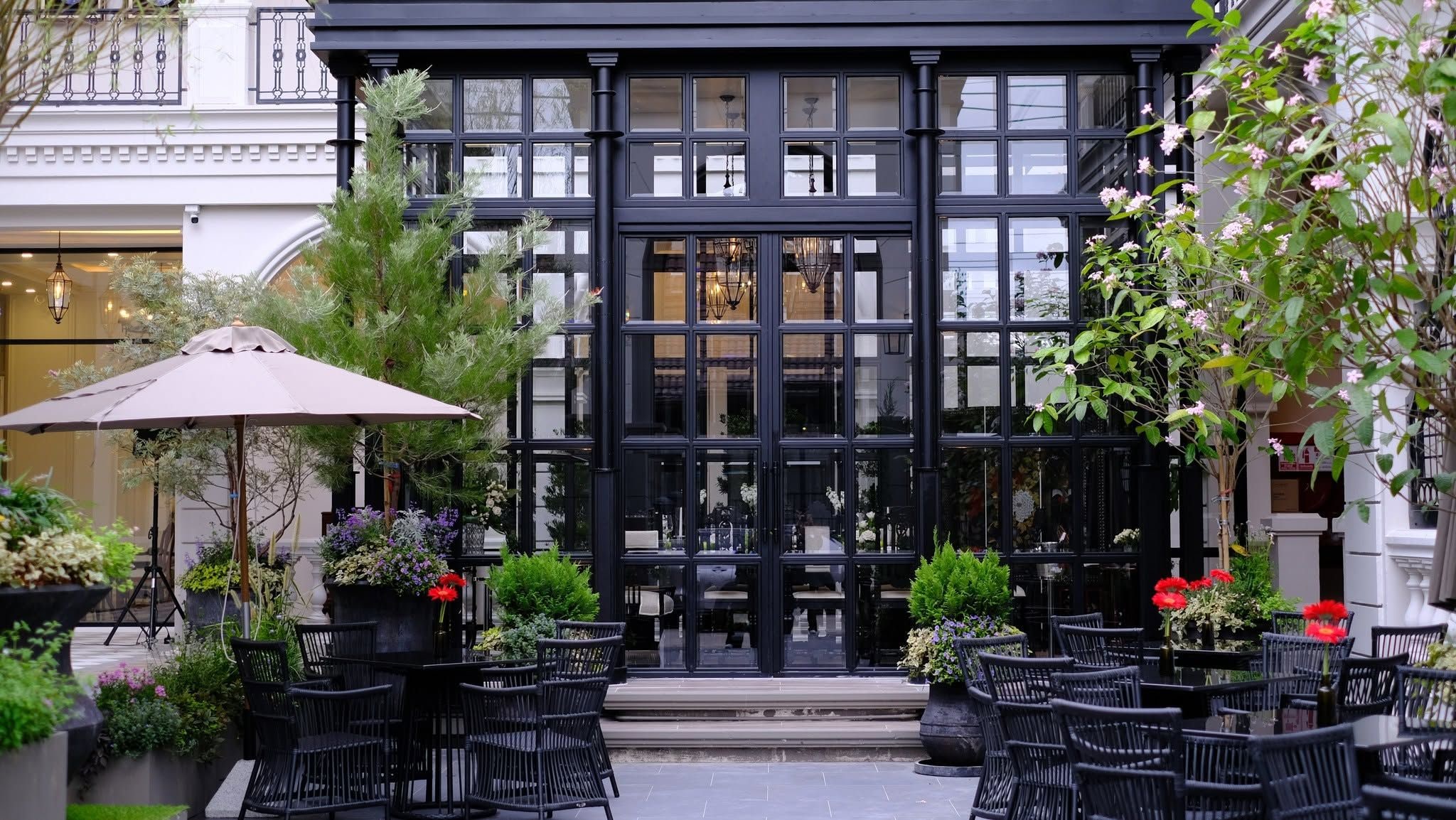 A building with a black facade, large windows, and outdoor seating with tables and chairs.