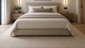 A modern bedroom with a large bed, bedside tables, a wall-mounted light, and a framed picture. - Serenity Villa (Beccles)