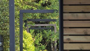 A pathway leading through a garden with a wooden pergola structure. - Serenity Villa (Beccles)