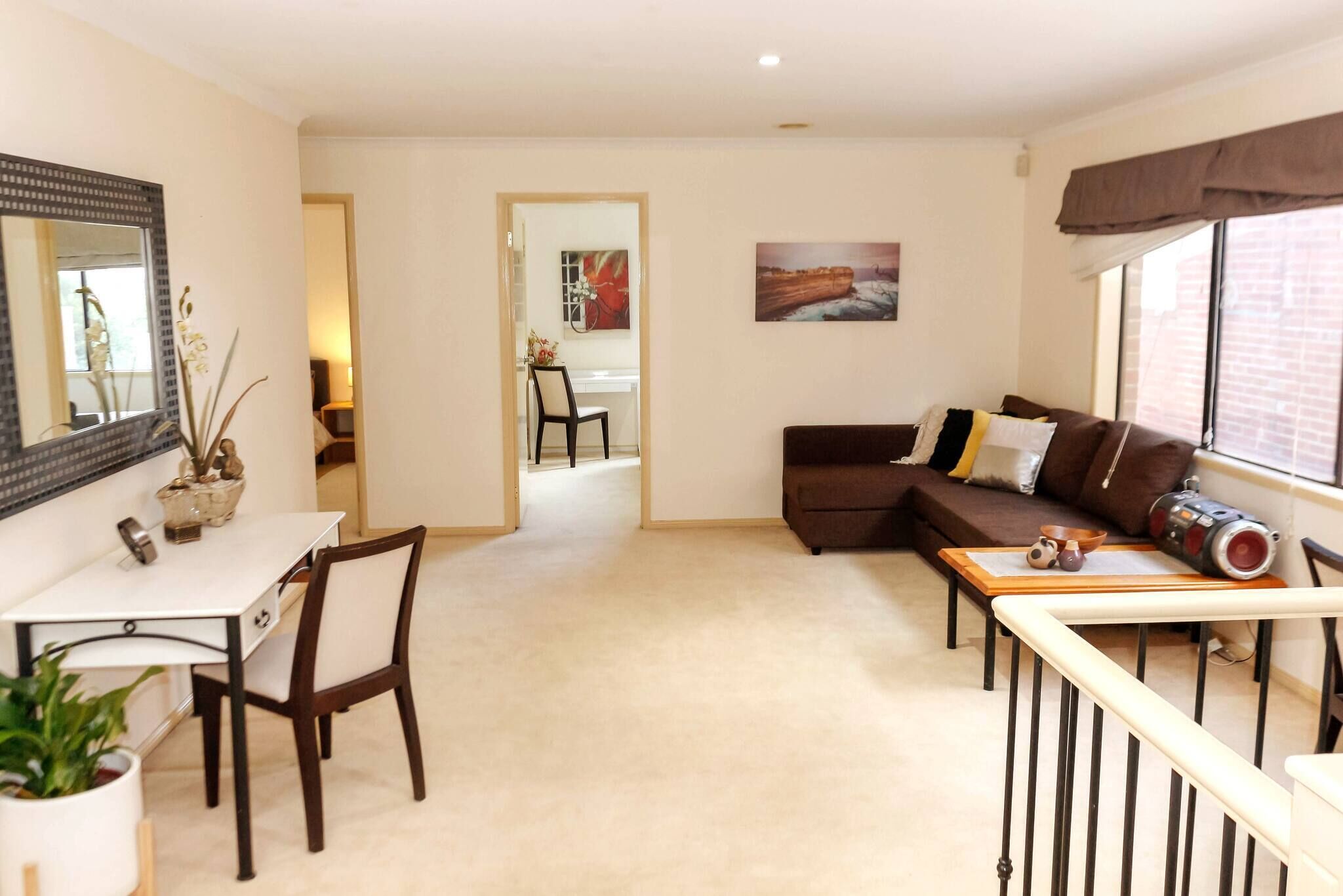 A living room with a sofa, a dining table, and a kitchen in the background.