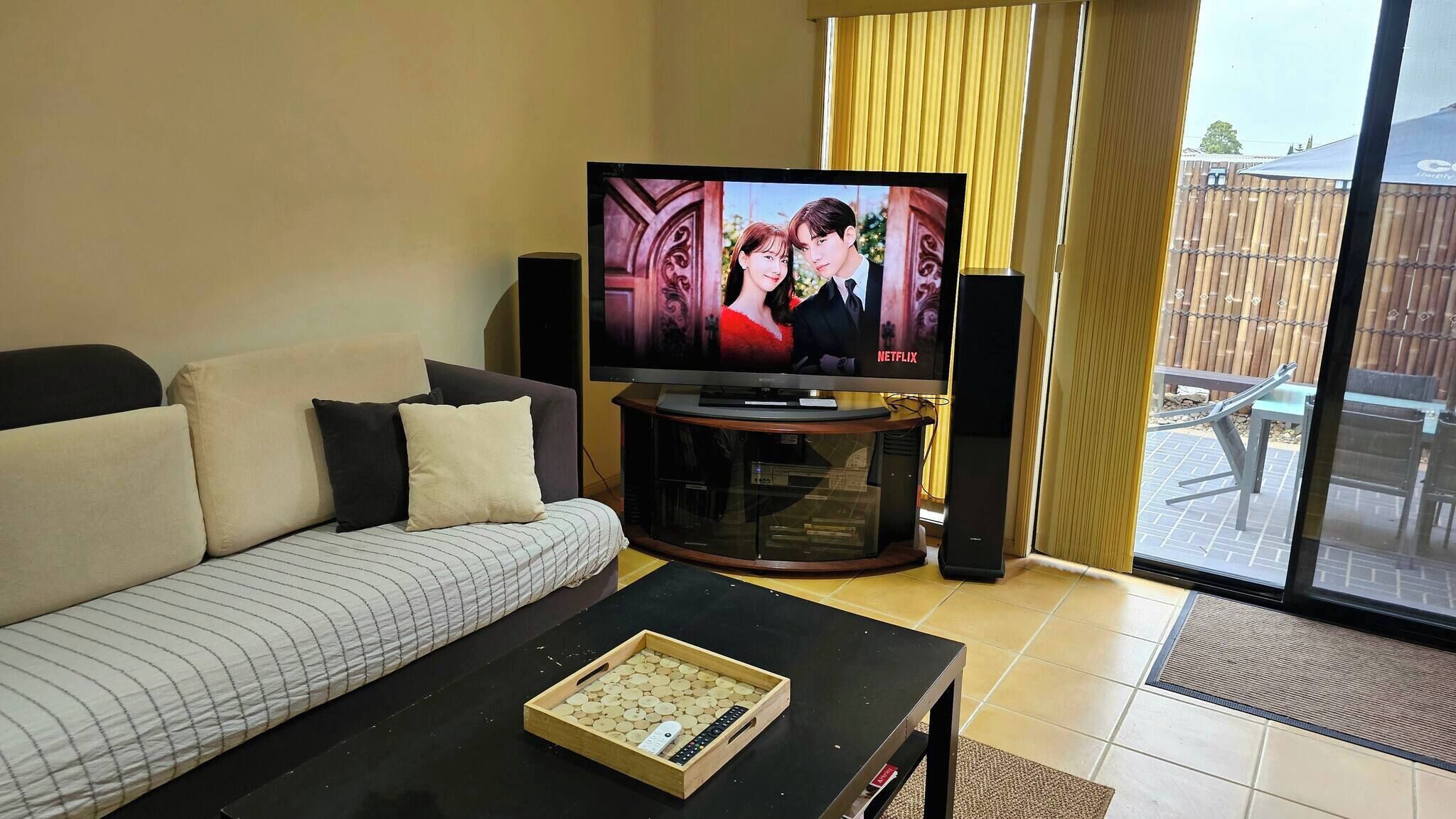Una sala de estar con un sofá, una mesa de centro con una bandeja de aperitivos, un televisor y altavoces.