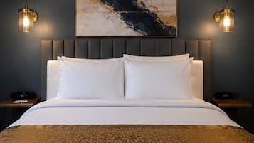 Een hotelkamer met een bed, hoofdeinde, twee nachtkastjes en een wanddecoratie.
