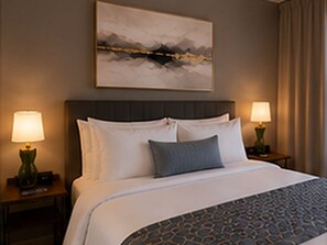 Quarto de hotel com uma cama, duas luminárias de cabeceira, uma mesinha de cabeceira, um quadro pendurado na parede e uma cortina.