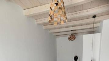Ein Zimmer mit einem Bett, einem runden Korbstuhl, einem kleinen weißen Tisch und einer Pendelleuchte.