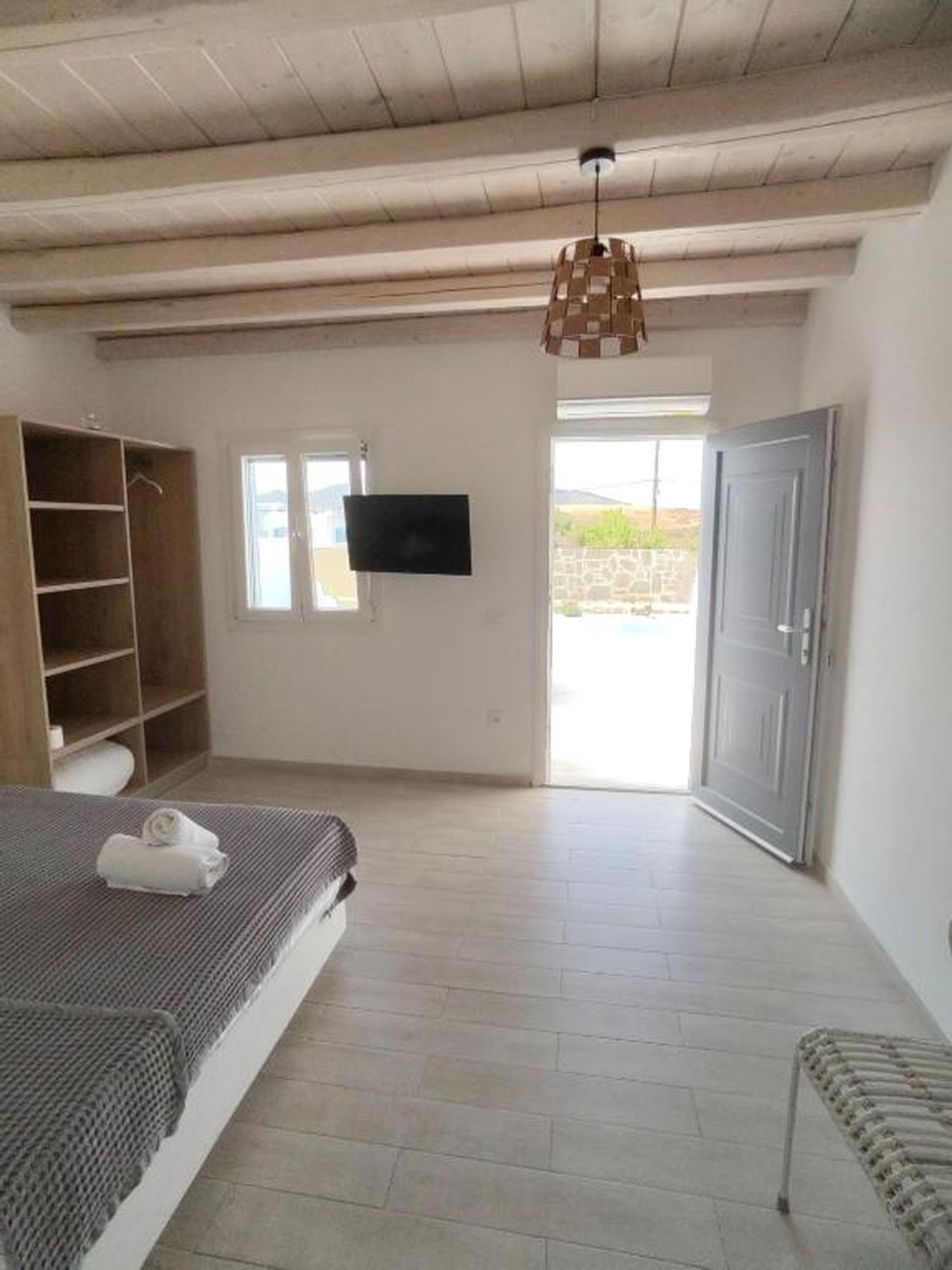 Ein Schlafzimmer mit einem Bett, einem Kleiderschrank, einem Fernseher und einer zur Außenwelt führenden Tür.