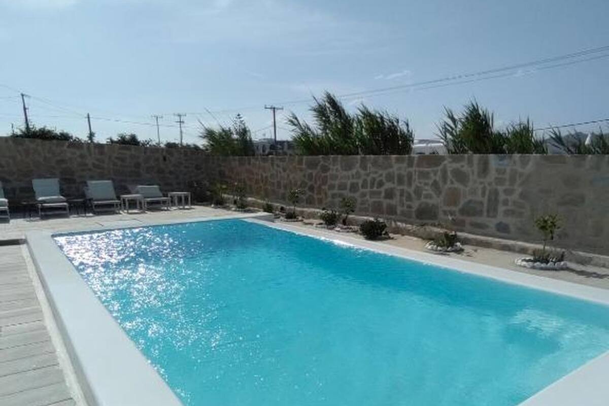 Una piscina rectangular con un muro de piedra y una cubierta de madera.
