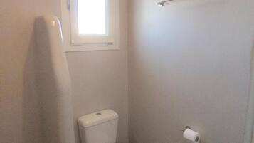 A small, white bathroom with a toilet, a window, and a towel rack.