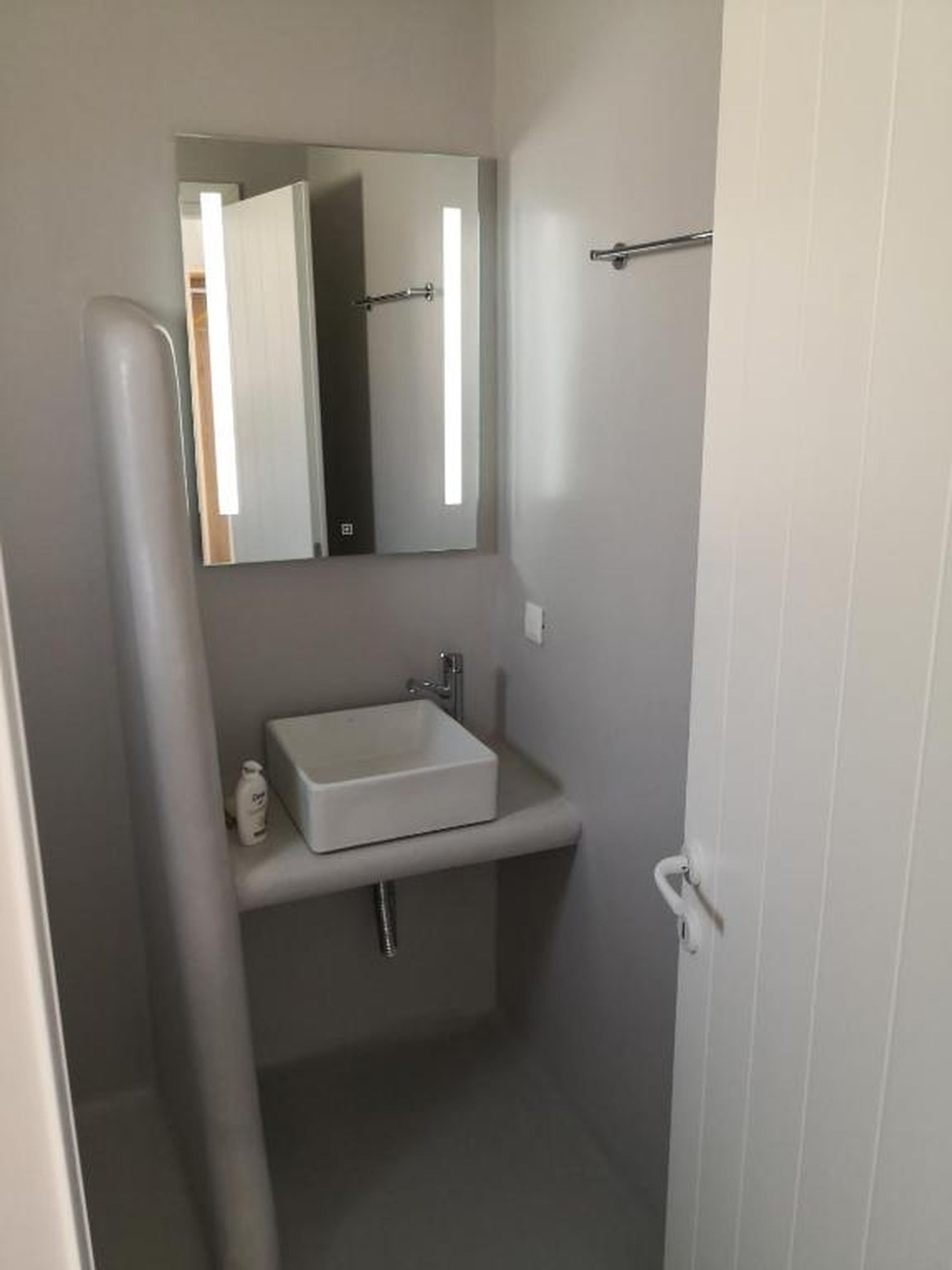 A bathroom with a white sink, a mirror, and a door.