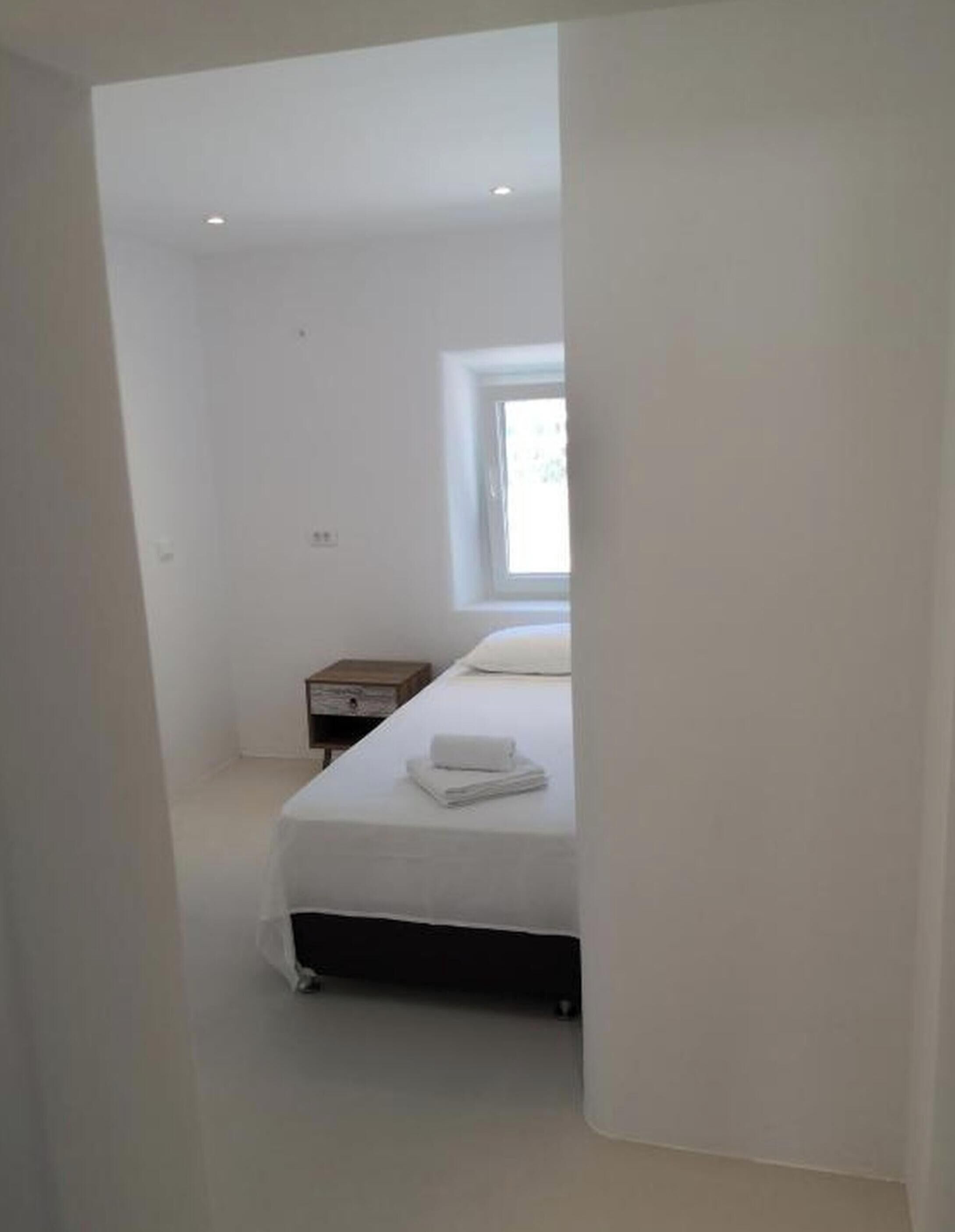 Una camera da letto minimalista con un letto, un comodino e una finestra.