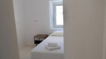 Una camera da letto minimalista con un letto, un comodino e una finestra.