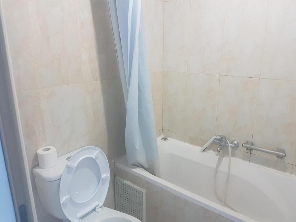 A bathroom with a toilet, a bathtub, and a shower curtain.