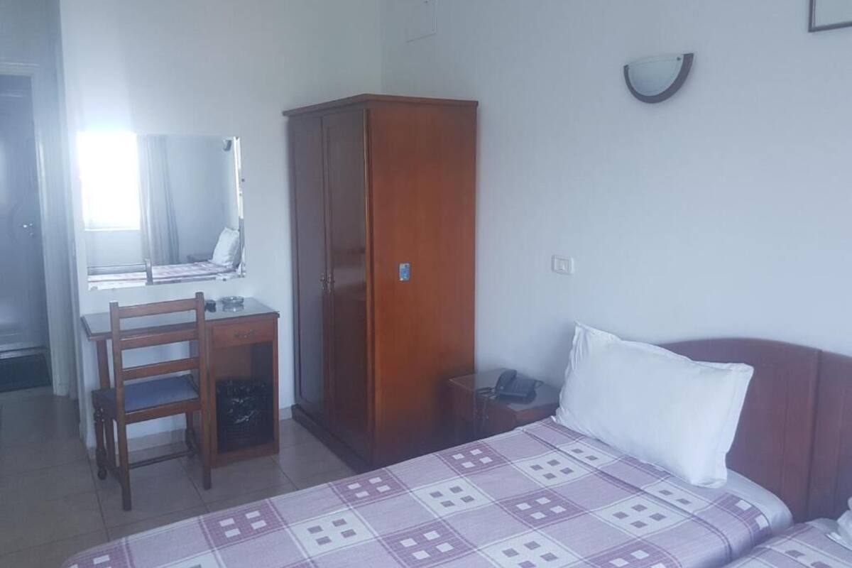 Una habitación con cama, escritorio, armario y espejo.