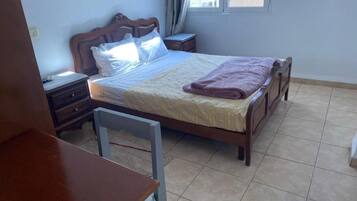 A bedroom with a bed, bedside tables, a chair, and a window.