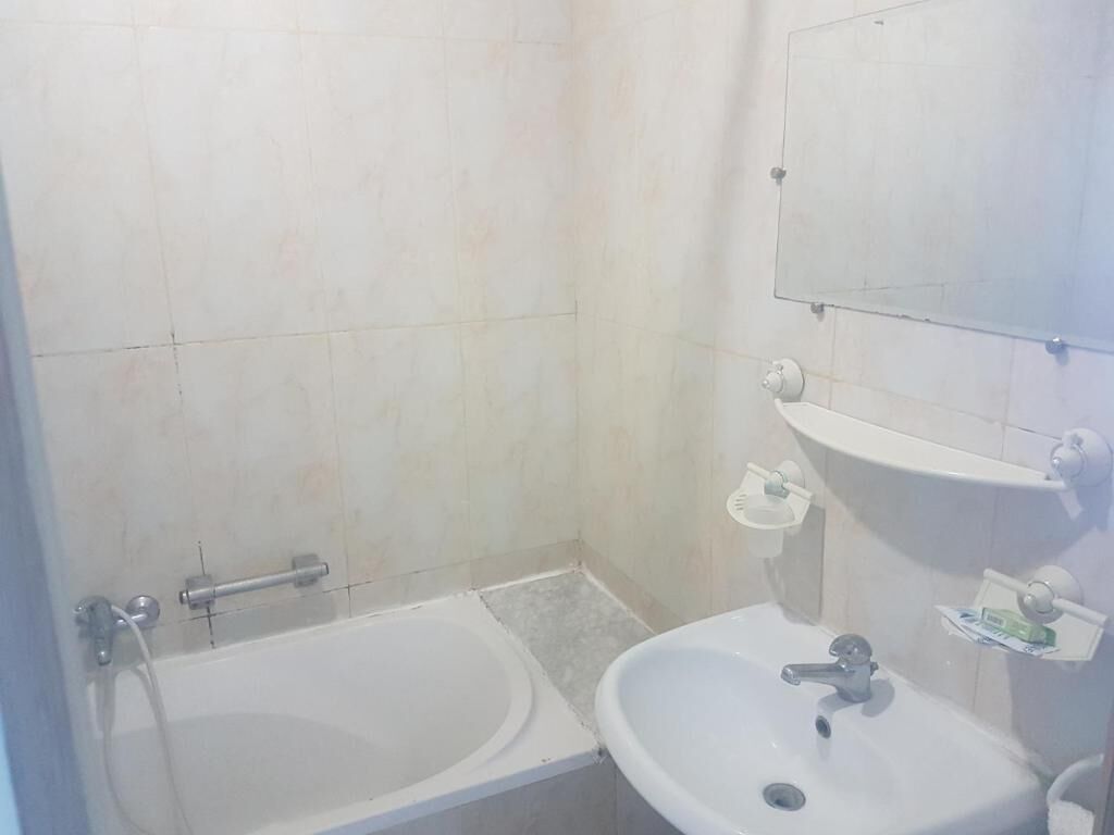 A bathroom with a bathtub, a sink, and a mirror.