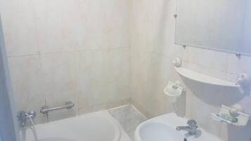 A bathroom with a bathtub, a sink, and a mirror.