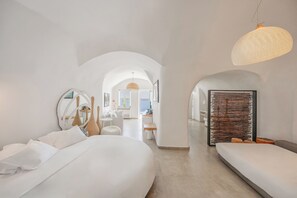 Una habitación de hotel moderna con una cama grande, una zona de estar y vistas al mar.