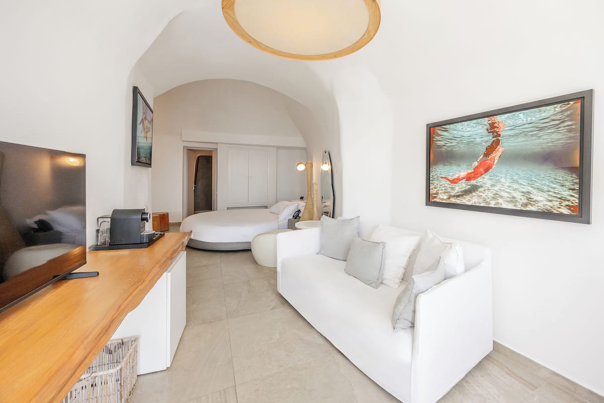 Ein modernes Wohnzimmer mit einem weißen Sofa, einem Couchtisch aus Holz, einem Flachbildfernseher und einem Gemälde einer Meerjungfrau.
