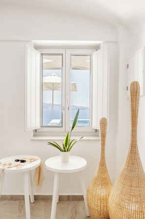 Ein Zimmer mit Meerblick, eine Topfpflanze, zwei Korbwannen und ein kleiner Tisch mit einem Handtuch.