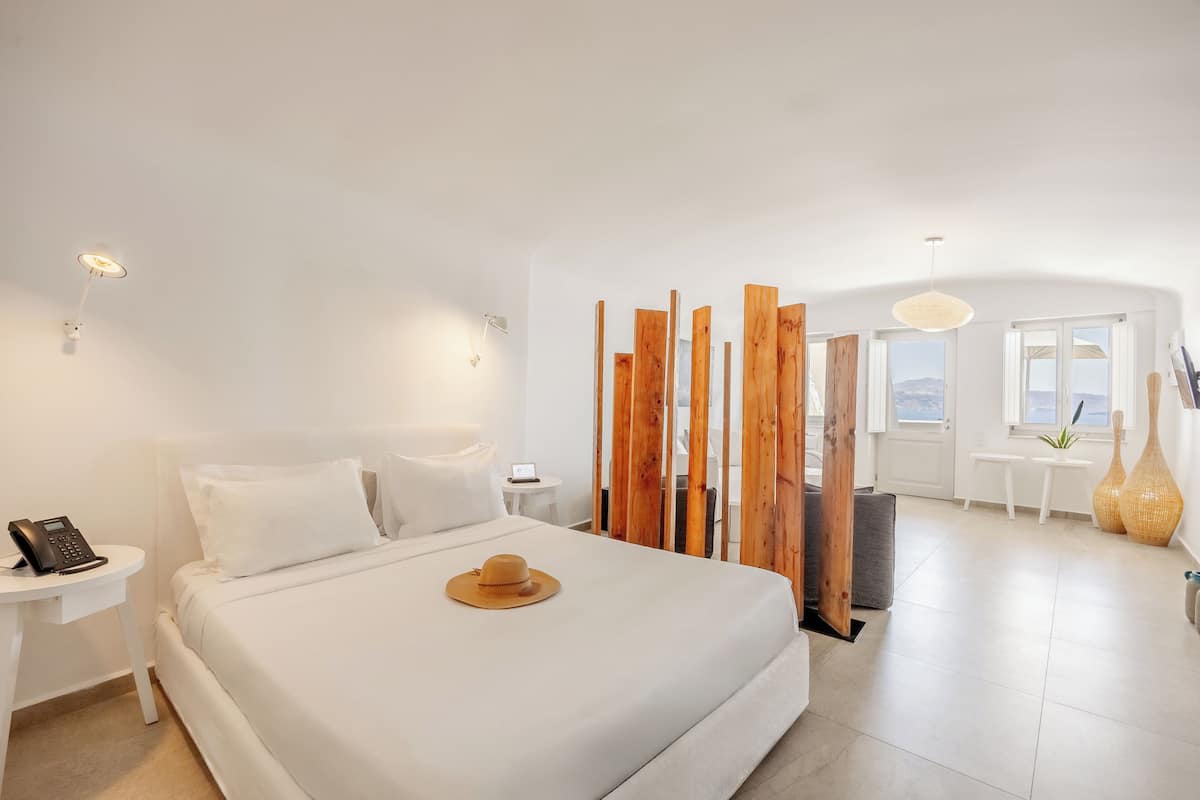 Ein modernes Hotelzimmer mit einem großen Bett, einem Nachttisch und Blick ins Freie.