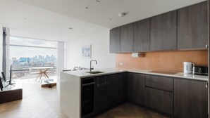 Una cucina moderna con mobili in legno scuro, un lavello in acciaio inossidabile e vista sulla città attraverso ampie finestre.