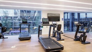 Una palestra moderna con tapis roulant, cyclette e vogatore, con ampie finestre e vista sulla città.