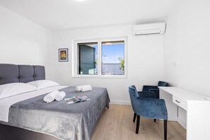 A hotel room with a bed, a desk, and a chair. There is a window with a view of the outside. - Holiday Home Eros With Pool (Sibenik)